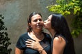 Mom with her teenage daughter getting a kiss and hug