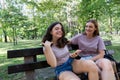 Mom and her teenage daughter have fun laughing on a walk in a summer park. Using a smartphone Royalty Free Stock Photo