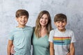 A mom and her two young and tween boys in a studio setting on a white gray background