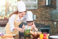 Mom and his little daughter cooking bolognese sauce for salad in the kitchen, there is steam escaping from the pan on cooking Royalty Free Stock Photo