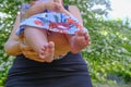 Mom holding a baby girl in her hands from beneath. Cute small newborn`s feet close-up on sunny day. Walking with a newborn in park Royalty Free Stock Photo