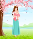 Mom holding baby in sling. Young mother under blossoming tree