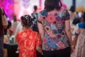 mom holding hand of girl with red China satin qipao cheongsam