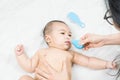 Mom holding her body to a small boy with her hands sucks the snot from the baby`s nose lying on the bed through the aspirator.