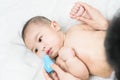 Mom holding her body to a small boy with her hands sucks the snot from the baby`s nose lying on the bed through the aspirator.