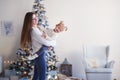 Mom holds her daughter in her arms, spinning. girls in white sweaters in a bright room, in the background a Christmas tree