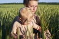 Mom holds her little son on a wheat field in summer