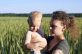 Mom holds her little son on a wheat field in summer