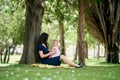 Mom holds a little girl on her lap while sitting near a tree on the lawn Royalty Free Stock Photo