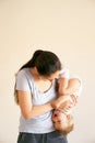 Mom holds a little laughing girl upside down in her arms