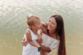 Mom hugging daughter on the beach near lake. The concept of summer holiday. Mother`s, baby`s day. Spending time together. Family Royalty Free Stock Photo