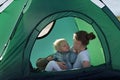 Mom hugs baby while lying in tent. Camping rest. Tourism, travel, outdoor activities