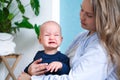 Mom hugs crying moody kid tantrum. Little baby child on mother hands. Family life, motherhood