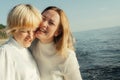 Mom hugs her daughter on the beach by the sea.