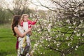 Mom hugs kisses daughter in the lush spring garden