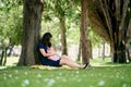 Mom hugs a little girl on her knees while sitting near a tree on the lawn Royalty Free Stock Photo