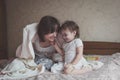 Mom hugs and plays with her daughter hide and seek on bed, life Royalty Free Stock Photo