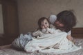 Mom hugs and plays with her daughter hide and seek on bed, life Royalty Free Stock Photo
