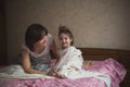 Mom hugs and plays with her daughter hide and seek on bed, life Royalty Free Stock Photo