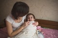 Mom hugs and plays with her daughter hide and seek on bed, life Royalty Free Stock Photo