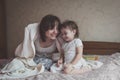 Mom hugs and plays with her daughter hide and seek on bed, life Royalty Free Stock Photo