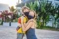 Mom hugs a sad son on the sidewalk in the city. Mother and baby wear face mask during coronavirus and flu outbreak Royalty Free Stock Photo