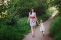 Mom keeps daughter's hand and walks the walk on the nature in sunset light