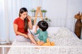 Mom and kid playing as doctor together on the bed. Woman lifestyle and family activity.