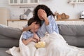 Mom and kid son with bowl of popcorn watching scary movie closing their eyes sitting on sofa at home Royalty Free Stock Photo