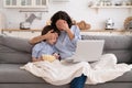 Mom and kid son with bowl of popcorn watching scary movie closing their eyes sitting on sofa at home Royalty Free Stock Photo