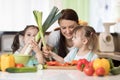 Mom and kids daughters have a fun preparing vegetables in a family home kitchen. Royalty Free Stock Photo