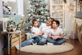 Mom and kids decorate the Christmas tree indoors. Happy family. Royalty Free Stock Photo