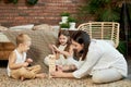 Mom and kids play squirl jenga tower. Woman girl and boy play family puzzle game. Family day off.