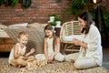 Mom and kids play squirl tower. Woman girl and boy play family puzzle game. Family day off Royalty Free Stock Photo