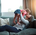 Mom, kiss and lifting girl on sofa in home living room and relax, bonding and quality time together or mother, love and Royalty Free Stock Photo