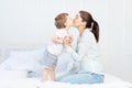 Mom kisses baby at home on the bed, the concept of family and children, mother`s day Royalty Free Stock Photo