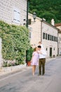 Mom kisses dad, holding little daughter on his shoulders. Family walks down the street with ancient buildings and Royalty Free Stock Photo