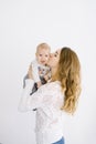 Mom kisses her baby on the cheek, the child smiles. Portrait on white background. Copy space. The concept of a happy motherhood Royalty Free Stock Photo