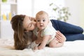 Mom kissing her little son on bed. Mother embracing infant baby. Royalty Free Stock Photo