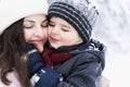 Mom kissing little stylish smiling happy cute boy, kid. Lovely family walking,activity in beautiful winter forest, park.Trees Royalty Free Stock Photo