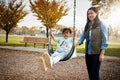 Mom knows how to make her childhood fun. a mother pushing her little daughter on a swing at the park.