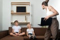 Mom with laptop in her hands and two boys on couch. Mother took laptop away from children