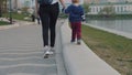 Mom leads the baby's hand. Mother and son are walking along the promenade.