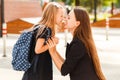 Mom leads her daughter to school. Return to school. Woman and girl with backpack behind the back. Beginning of lessons Royalty Free Stock Photo