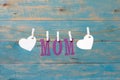 MOM letters. Mothers day message with hearts hanging with clothespins over blue wooden board Royalty Free Stock Photo