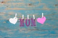 MOM letters. Mothers day message with hearts hanging with clothespins over blue wooden board Royalty Free Stock Photo