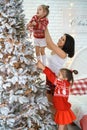 Mom lifts the child high so that he can hang a ball on the Christmas tree Royalty Free Stock Photo