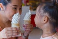 Mom and little child eating ice scream cone together . feeling enjoyment