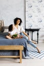 Mom and little cute curly girl sitting on bed with tulips in their hands Royalty Free Stock Photo