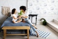 Mom and little cute curly girl sitting on bed with tulips in their hands Royalty Free Stock Photo